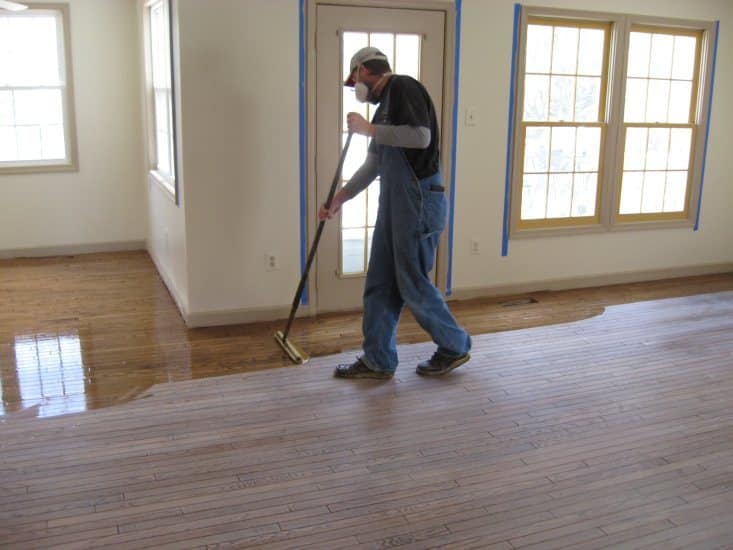worker finishes floor with polyurethane