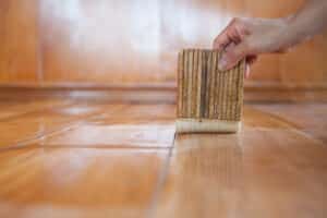 worker adds a polyurethane coating to hardwood floor