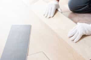 worker installs luxury vinyl floor with white gloves