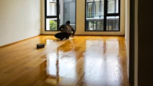 worker applying polyurethane to hardwood floor